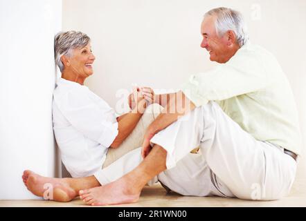 Couple d'âge mûr heureux passant du temps à la maison. Heureux couple d'âge mûr passant du temps à la maison tout en étant assis sur le sol. Banque D'Images