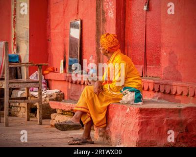 Varanasi, Inde - 13 novembre 2015. Un coiffeur indien portant des vêtements traditionnels attend les clients dans un espace extérieur de fortune. Banque D'Images