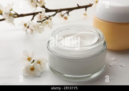 Pots de crème pour le visage et fleurs sur une table en marbre blanc Banque D'Images