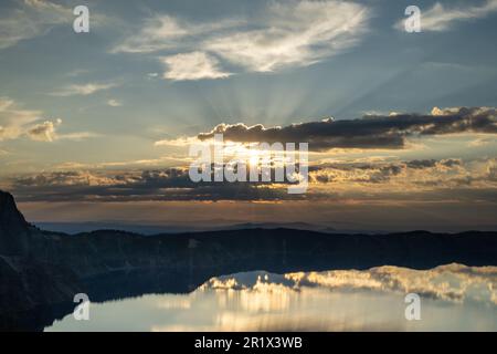 Le soleil se brise à travers les nuages sombres au-dessus du lac Crater juste après que le soleil monte en été Banque D'Images