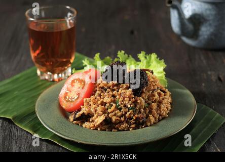 Nasi Goreng Rendang, riz frit avec ragoût de boeuf Randang avec lait de noix de coco et diverses épices. Servi avec une tranche de tomates Banque D'Images