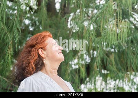 Portrait d'une femme latino-américaine aux cheveux rouges souriant, rêvant de rêver dans la nature. Composition lumineuse avec espace de copie. Concept: La paix de l'esprit et h Banque D'Images