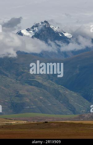Vue sur un pic enneigé spectaculaire dans la chaîne des Andes, vue depuis les terres agricoles de Maras au Pérou. Banque D'Images