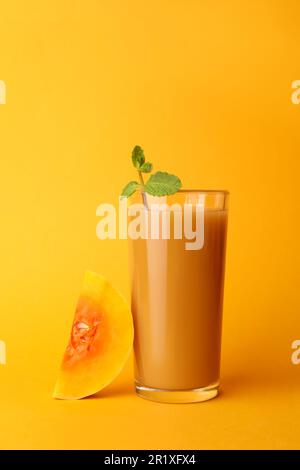 Délicieux jus de citrouille en verre et couper la citrouille sur fond orange Banque D'Images