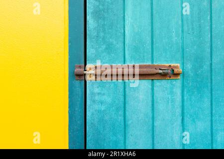 Un cadenas fermé est fixé sur les portes murales jaunes et bleues. Banque D'Images