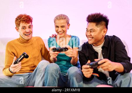 Heureux amis multiethniques jouant à la console à la maison Banque D'Images