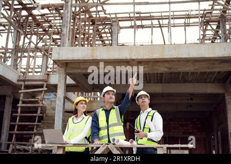 Asian Architector et équipe d'ingénieurs avec projet de plan de construction et de tablette parlant site de construction. Directeur de construction et ingénieur travaillant sur le bu Banque D'Images