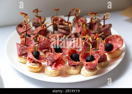 Délicieux canapés de chorizo, salami sur brochettes servis sur une assiette avec des olives et du pain - l'apéritif parfait pour tous les repas ou buffets Banque D'Images