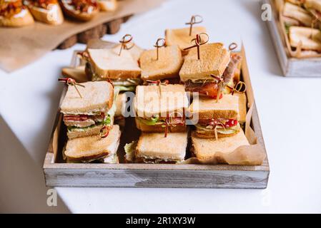 Prêt à manger variété de mini sandwiches sur un plateau en bois Plateau en bois rempli d'une variété de mini sandwiches, prêts à manger, pour un agréable et fr Banque D'Images