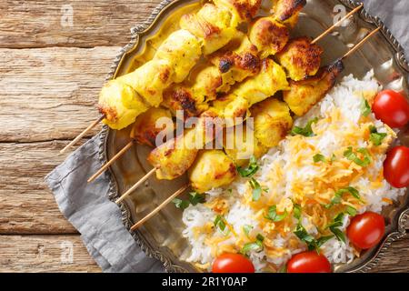 Brochettes de poulet grillé au safran avec riz décorent en gros plan dans une assiette sur une table en bois. vue horizontale du dessus Banque D'Images