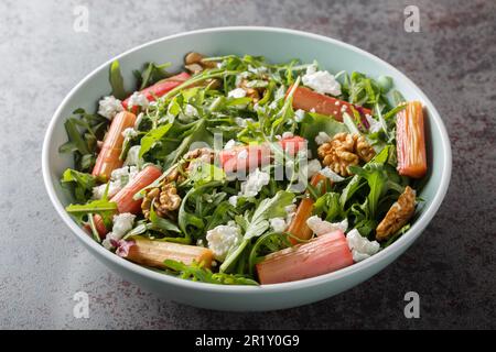 Salade de régime avec rhubarbe cuite au four, arugula, fromage de chèvre et noix de Grenoble dans un bol sur la table. Horizontale Banque D'Images