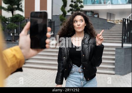 Une personne qui enregistre une jeune femme influenceur blogueur sur un smartphone Banque D'Images