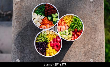 Vue verticale rapprochée de trois poke-bols avec légumes, fruits, poisson et salade d'algues Banque D'Images