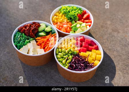 Vue rapprochée de trois poke-bols avec légumes, fruits, poisson et salade d'algues Banque D'Images