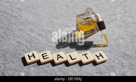 flacon de pipette rectangulaire avec liquide doré - santé orthographié en lettres Banque D'Images