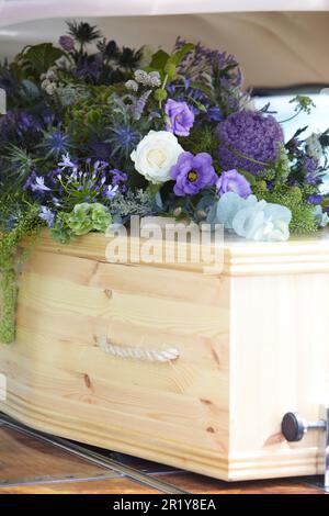 Gros plan de cercueil en bois Uni avec hommages floraux au dos des cœurs de l'art funéraire Banque D'Images