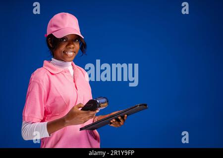 Image de jeune belle ventes noir femme travailleur debout tenant et utilisant le terminal de pos pour le retrait d'argent sans espèces Banque D'Images