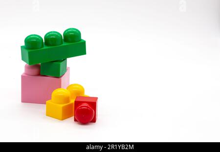 Constructeur de jouets pour enfants lego différentes tailles. Blocs rouge, rose et jaune et vert. Photo de haute qualité. Isolé. Banque D'Images