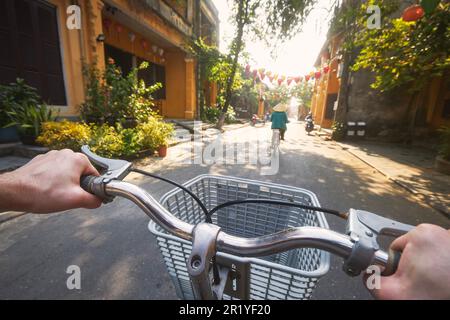 POV vélo de tourisme dans la ville antique de Hoi an au Vietnam. Mise au point sélective sur le guidon de la main. Banque D'Images