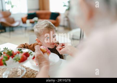 Petit garçon mangeant des beignets de fraise avec sa grand-mère. Banque D'Images