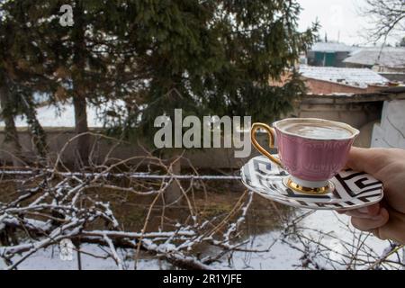 Café turc bu dans une tasse rose dans un jardin enneigé. Banque D'Images