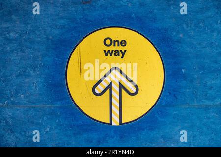 Un panneau sur un étage indiquant un système à sens unique le long d'un couloir, une gueule de bois de la pandémie Covid-19. Banque D'Images