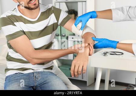 Médecin appliquant le bandage sur le bras du patient à l'hôpital, gros plan Banque D'Images