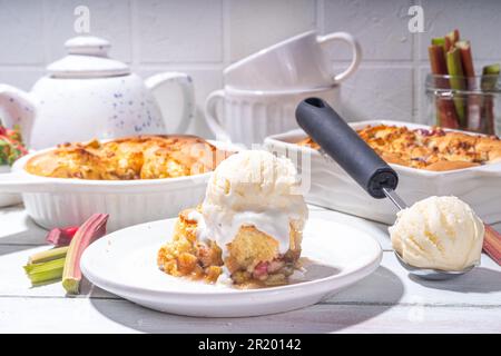 Tarte parée à la framboise aux baies, gâteau maison à l'éponge avec rhubarbe sucrée et fraise, servi avec boule de glace à la vanille, sur un k en bois blanc ensoleillé Banque D'Images