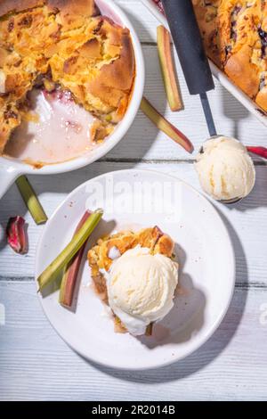 Tarte parée à la framboise aux baies, gâteau maison à l'éponge avec rhubarbe sucrée et fraise, servi avec boule de glace à la vanille, sur un k en bois blanc ensoleillé Banque D'Images