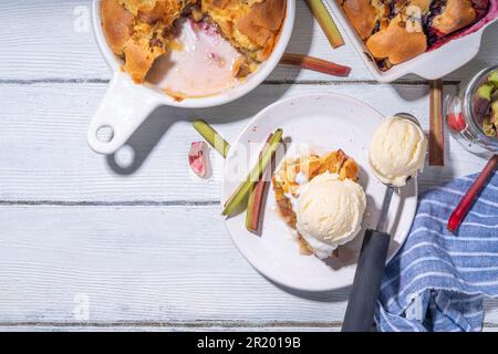 Tarte parée à la framboise aux baies, gâteau maison à l'éponge avec rhubarbe sucrée et fraise, servi avec boule de glace à la vanille, sur un k en bois blanc ensoleillé Banque D'Images