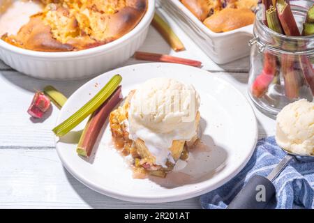 Tarte parée à la framboise aux baies, gâteau maison à l'éponge avec rhubarbe sucrée et fraise, servi avec boule de glace à la vanille, sur un k en bois blanc ensoleillé Banque D'Images