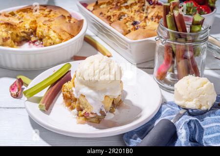 Tarte parée à la framboise aux baies, gâteau maison à l'éponge avec rhubarbe sucrée et fraise, servi avec boule de glace à la vanille, sur un k en bois blanc ensoleillé Banque D'Images