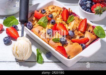 Tarte parée aux petits fruits d'été, gâteau maison avec myrtille sucrée et fraise, servi avec boule de glace à la vanille, sur bois blanc ensoleillé Banque D'Images