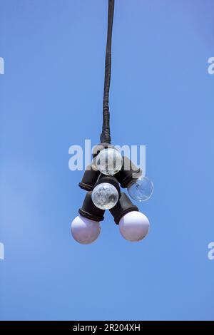 Beaucoup d'ampoules pendent avec un fond de ciel. Banque D'Images