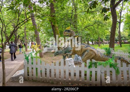 Adultes et enfants regardant les dinosaures animatroniques ou robotiques dans un parc Banque D'Images