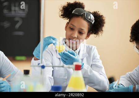 Portrait d'une jeune fille d'école noire profitant d'expériences scientifiques à l'école et travaillant avec la réaction chimique Banque D'Images