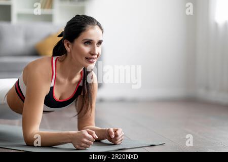 Gros plan de la jeune femme brunette motivée planking à la maison Banque D'Images