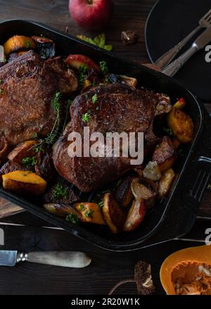 Plat à viande pour Thanksgiving avec queues de dinde rôties. Servi avec de la pumkine au noyer cendré, des pommes rouges, des oignons dans une rôtissoire sur une table rustique en bois Banque D'Images