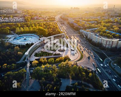 Vue aérienne par drone de l'arche d'entrée du Parc du Premier Président à Almaty, Kazakhstan. Avenue Alfarabi avec voitures de circulation au coucher du soleil au printemps tim Banque D'Images