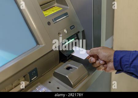 Détail de la main d'un homme insérant une carte vierge dans un guichet automatique. Banque D'Images