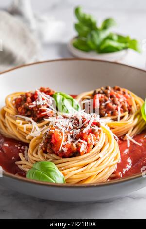 Spaghetti végétariens bolognaise avec lentilles dans une sauce tomate avec parmesan et feuilles de basilic. Concept alimentaire végétalien sain Banque D'Images