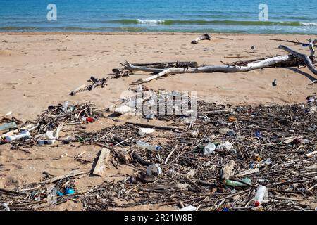 plage de déchets. Des bâtons, des branches et des bouteilles en plastique se trouvent sur le sable de la mer. Banque D'Images