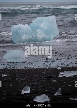 Les icebergs avec de petits morceaux flottant au-dessus d'eux sur la plage de Diamant Banque D'Images