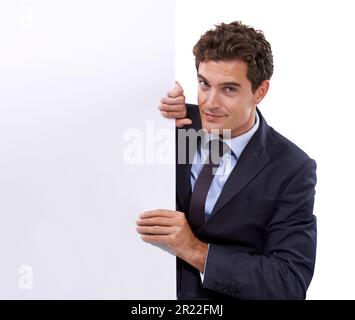 Rapprocher l'espace de copie. Un beau jeune homme d'affaires qui peeking hors de derrière le copyspace. Banque D'Images