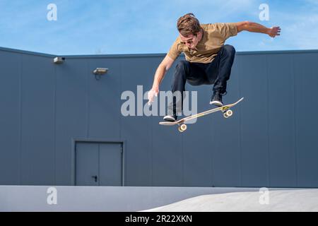 Skateboarder faisant le tour de l'ollie sur une scène urbaine. Banque D'Images