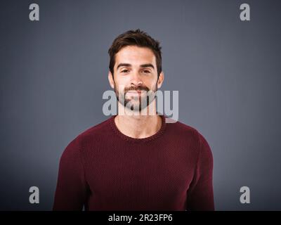 La confiance semble bonne sur lui. Photo en studio d'un jeune homme beau et confiant posant sur un fond gris. Banque D'Images