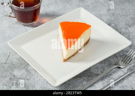 Cheesecake à la citrouille sur une assiette en porcelaine avec thé sur une table en pierre Banque D'Images