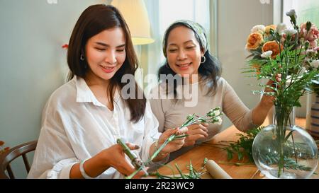 Photo d'une femme âgée heureuse et d'une fille adulte créant un beau bouquet à la maison. Concept d'activité familiale et de loisirs Banque D'Images