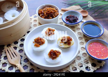 Gâteau au riz cuit à la vapeur avec navet conservé servi avec une sauce au soja et à la sauce Chili - dans la cuisine chinoise appelée Chwee Kueh sur une table en bois Banque D'Images