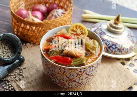 Curry rouge thaï avec gloire du matin et poitrine de porc - authentique cuisine thaïlandaise appelée Kang Tay po servi dans la porcelaine Benjarong Banque D'Images
